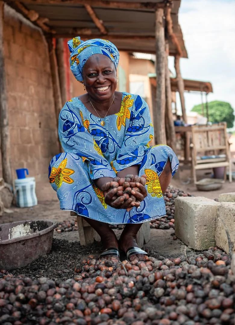 Productrice de karité souriante tenant des amandes fraîchement triées